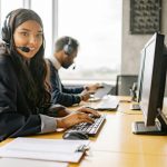 Smiling call center agents in an office providing customer support on computers.